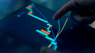 Fingers interacting with a stock market graph on a tablet.