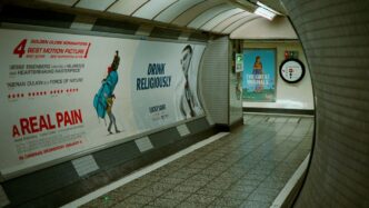 Subway tunnel with advertisements and tiled walls.