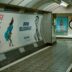 Subway tunnel with advertisements and tiled walls.