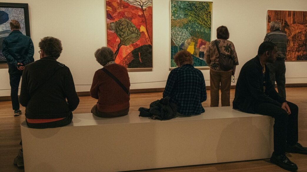 a group of people sitting on a bench in a museum