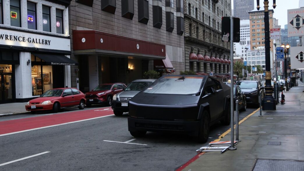 A black tesla cybertruck parked on a city street.