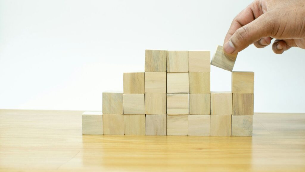A person placing a block into a pile of wooden blocks