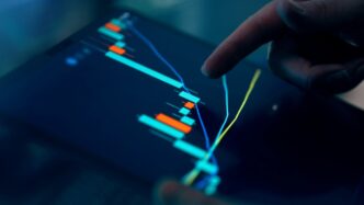 Fingers interacting with a stock market graph on a tablet.