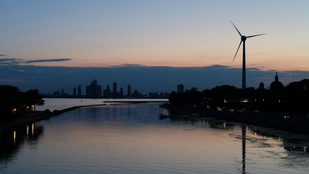 a body of water with a windmill in the distance