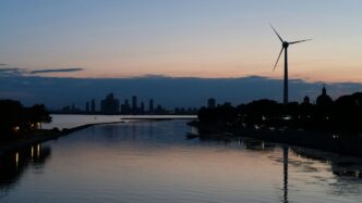 a body of water with a windmill in the distance