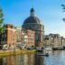 Canal in amsterdam with historic buildings and dome.