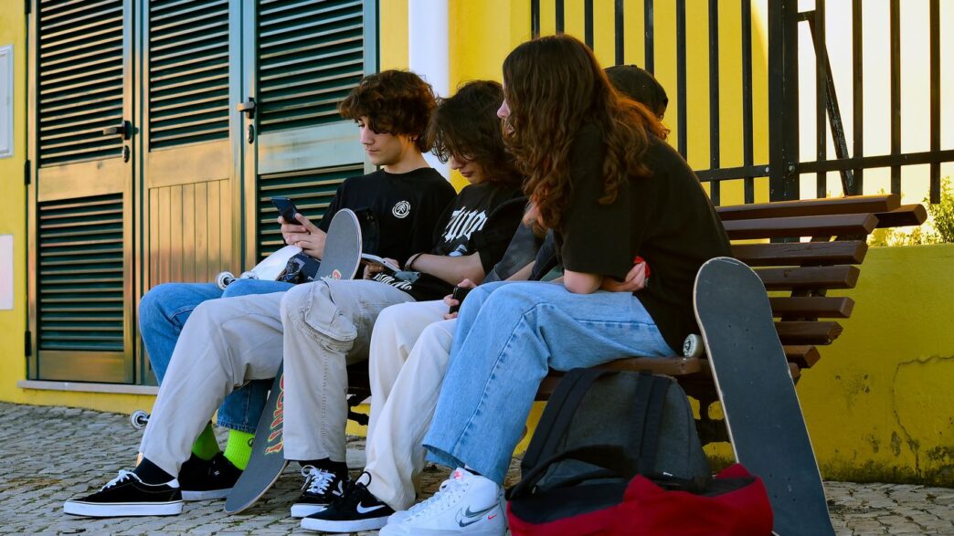 a group of people sitting on a bench with their laptops