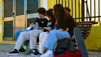 a group of people sitting on a bench with their laptops