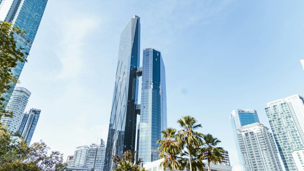 Modern skyscrapers and palm trees under a clear sky.