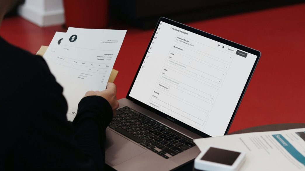 A person sitting at a desk with a laptop and papers