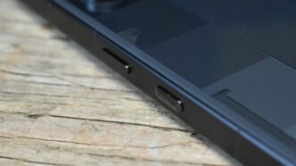 Close-up of a black smartphone on a wooden surface.