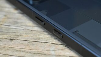 Close-up of a black smartphone on a wooden surface.