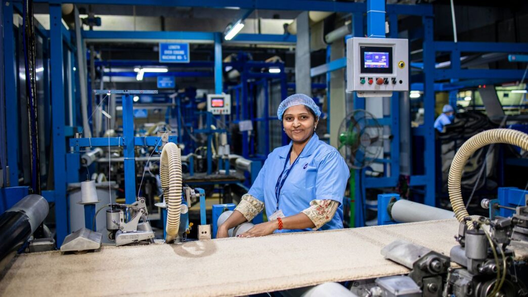 Factory worker smiles while operating machinery.