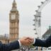 Handshake with UK landmarks in background.