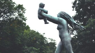 man holding a book statue