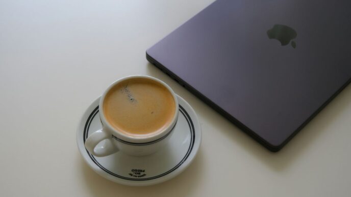 Espresso cup next to a closed laptop on white table