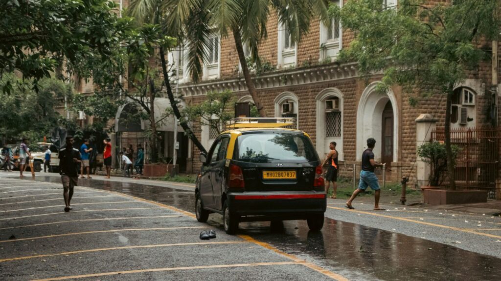 A yellow taxi and people on a wet street.