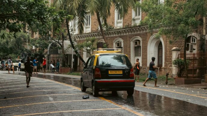 A yellow taxi and people on a wet street.