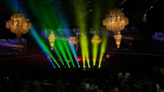 Stage lights illuminate an event with chandeliers.