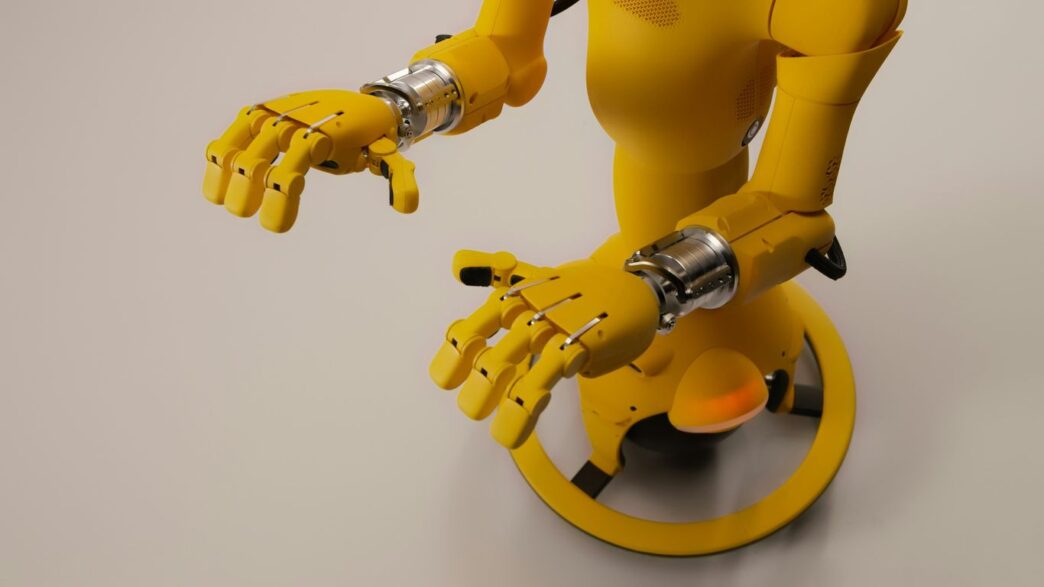 Yellow robot with articulated hands on a white background