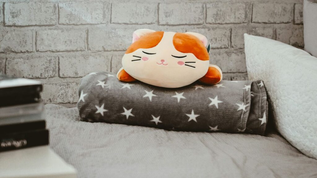 a cat pillow sitting on top of a bed