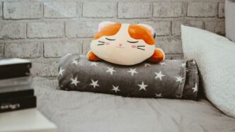 a cat pillow sitting on top of a bed