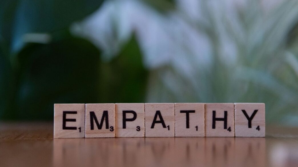 A wooden block spelling the word empathhy on a table