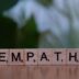 A wooden block spelling the word empathhy on a table