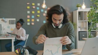 Man reviewing charts at a modern office desk.