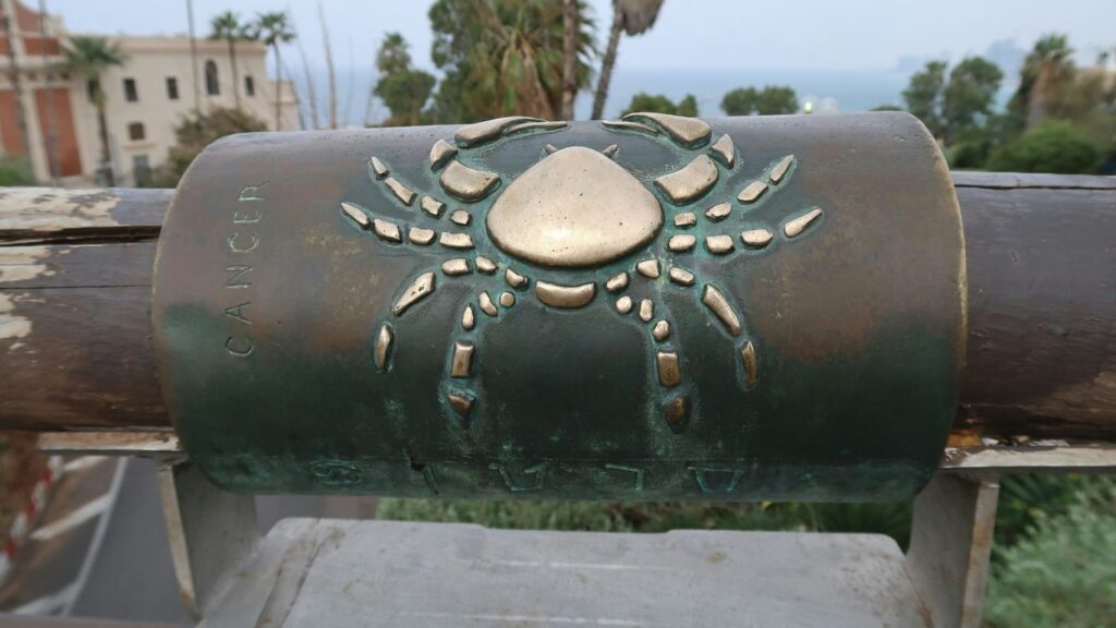 Bronze crab emblem on a cylindrical monument.