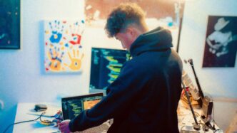Young man working on laptop and computer screens