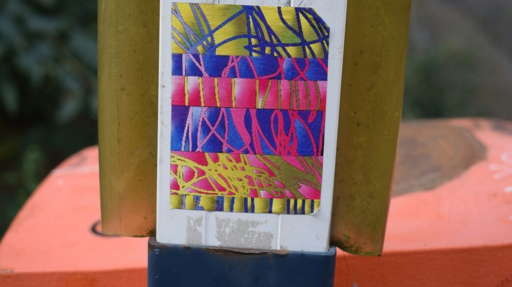 Colorful abstract sticker on a yellow pole.