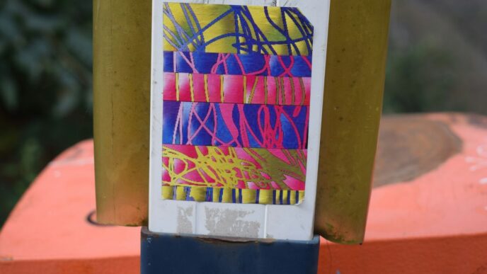 Colorful abstract sticker on a yellow pole.