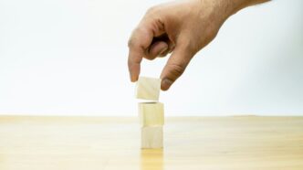 A hand is placing a block of wood on a table