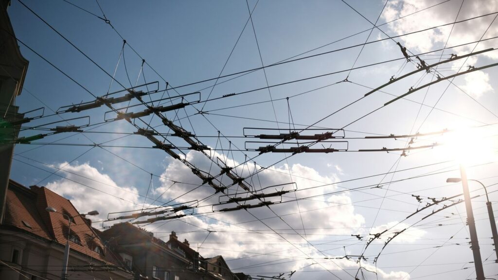 Overhead electrical wires against a sunny sky.