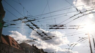 Overhead electrical wires against a sunny sky.