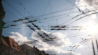 Overhead electrical wires against a sunny sky.