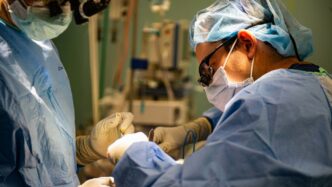 Surgeons in sterile gowns performing a medical operation.