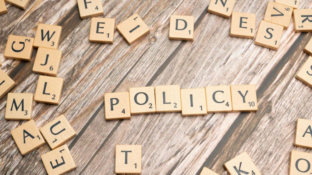 scrabble tiles spelling policy on a wooden table