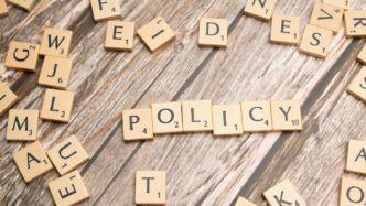 scrabble tiles spelling policy on a wooden table