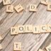 scrabble tiles spelling policy on a wooden table