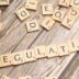 scrabble tiles spelling out the word regulation on a wooden surface
