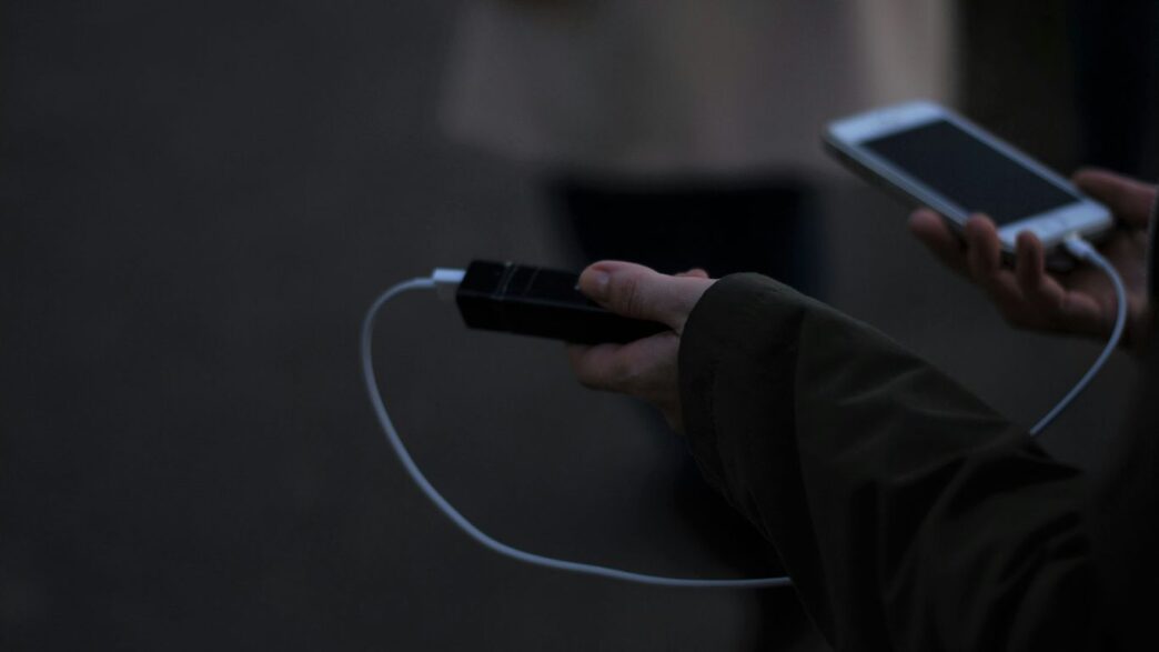 a person holding a cell phone and a charger