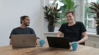 man in black crew neck shirt sitting beside brown wooden table