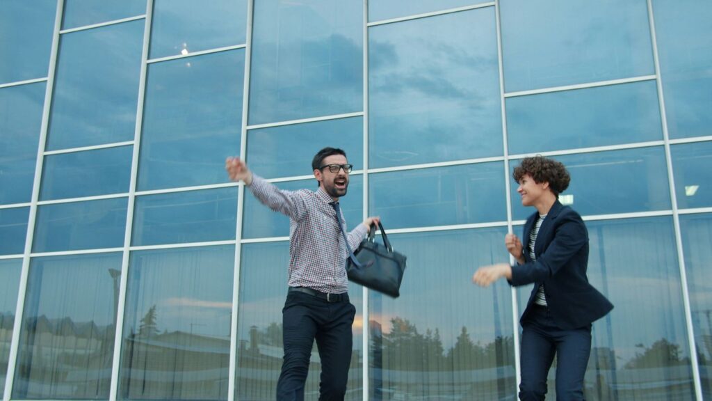 Two business people celebrating outside modern office building