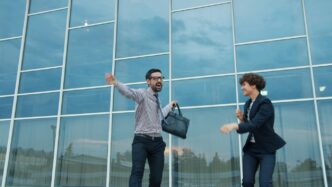 Two business people celebrating outside modern office building