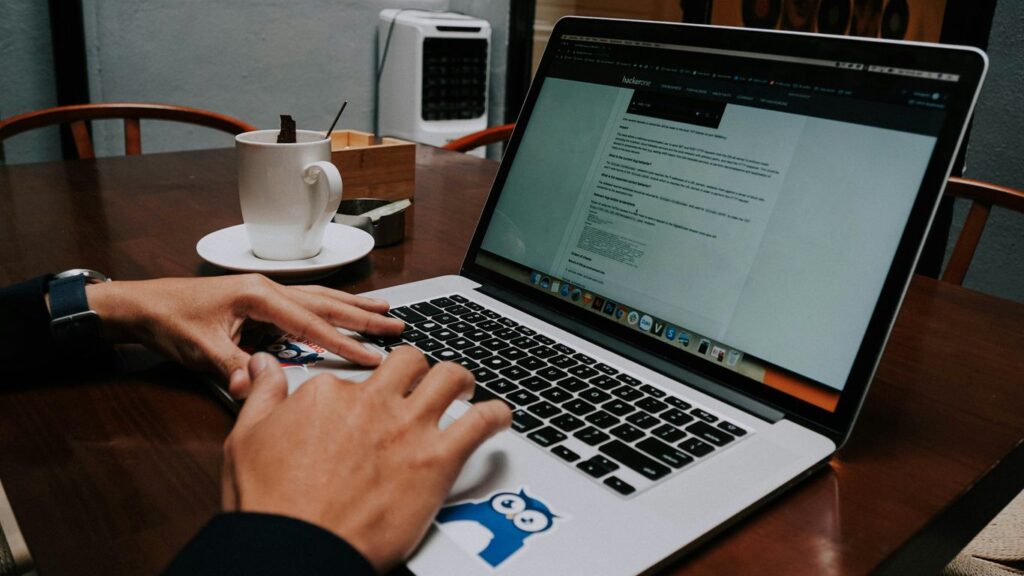 a person using a laptop on a wooden table
