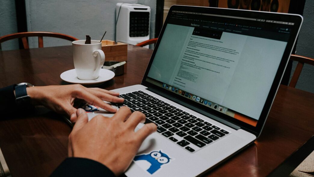 a person using a laptop on a wooden table
