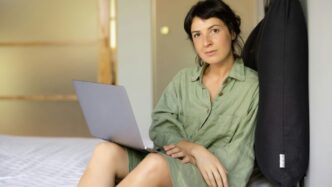a woman sitting on a bed using a laptop computer