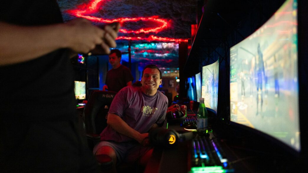 People playing video games in a dimly lit room.